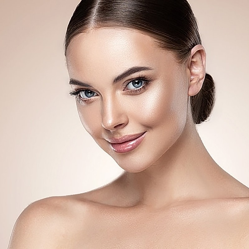 Smiling woman with glowing skin and blue eyes.