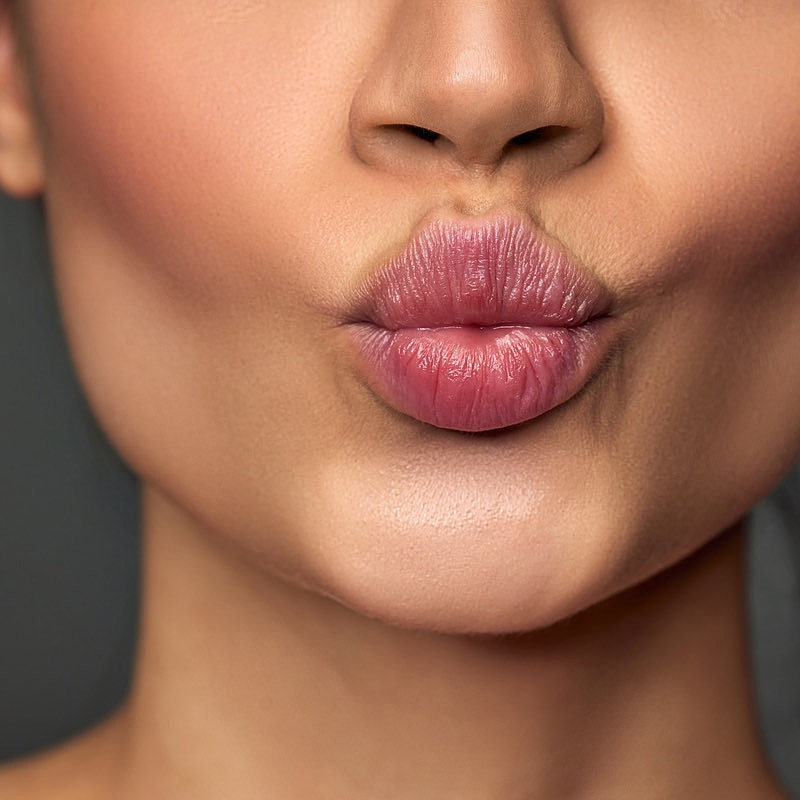Close-up of lips kissing or puckering gesture.