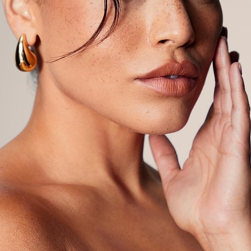 Close-up of woman with elegant earrings and makeup.