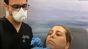 Medical professional performing facial treatment on patient.