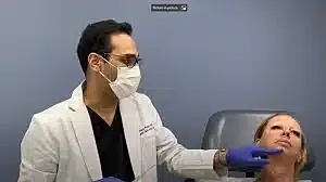 Medical professional performing facial treatment on patient.