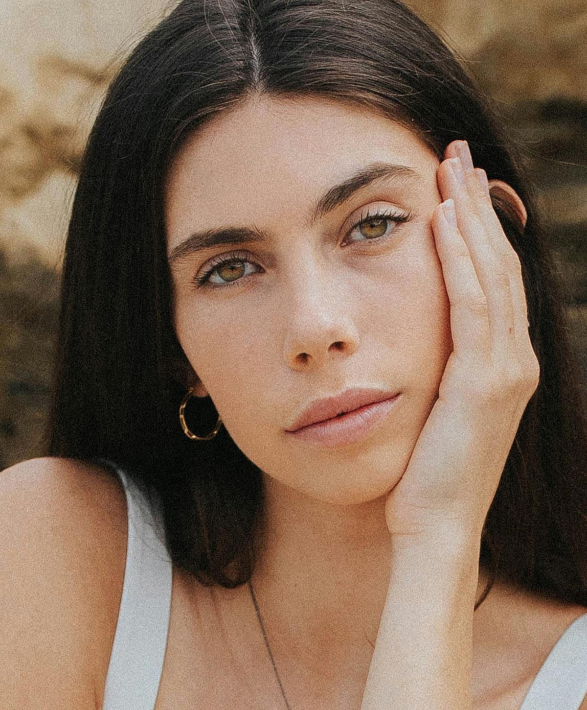 Young woman with hand on face, natural expression.