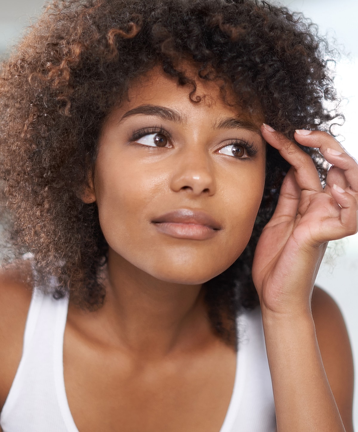 Woman with curly hair in thoughtful pose.