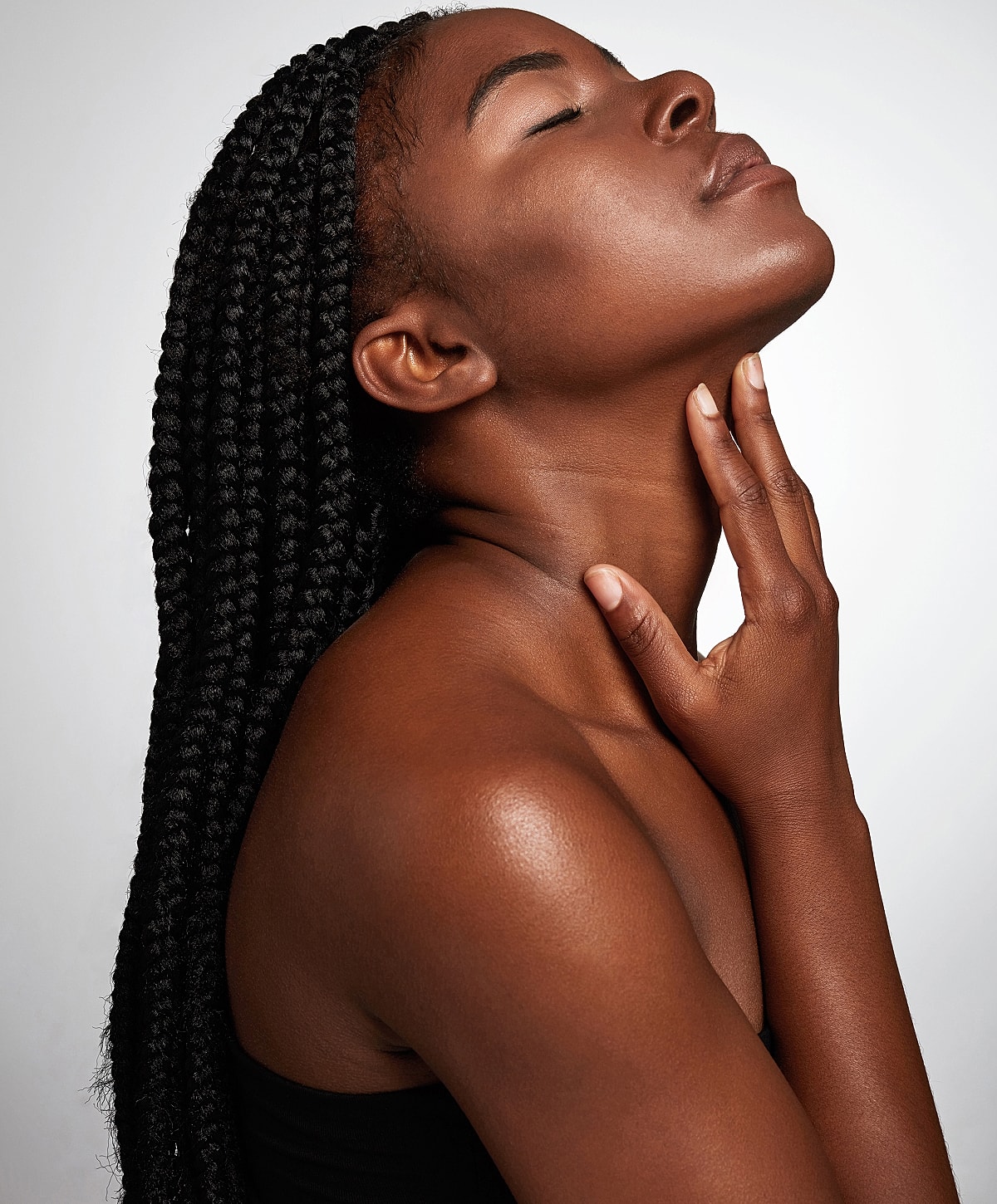 Woman with braids touching her neck gracefully.