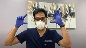 Doctor with mask and gloves gesturing.
