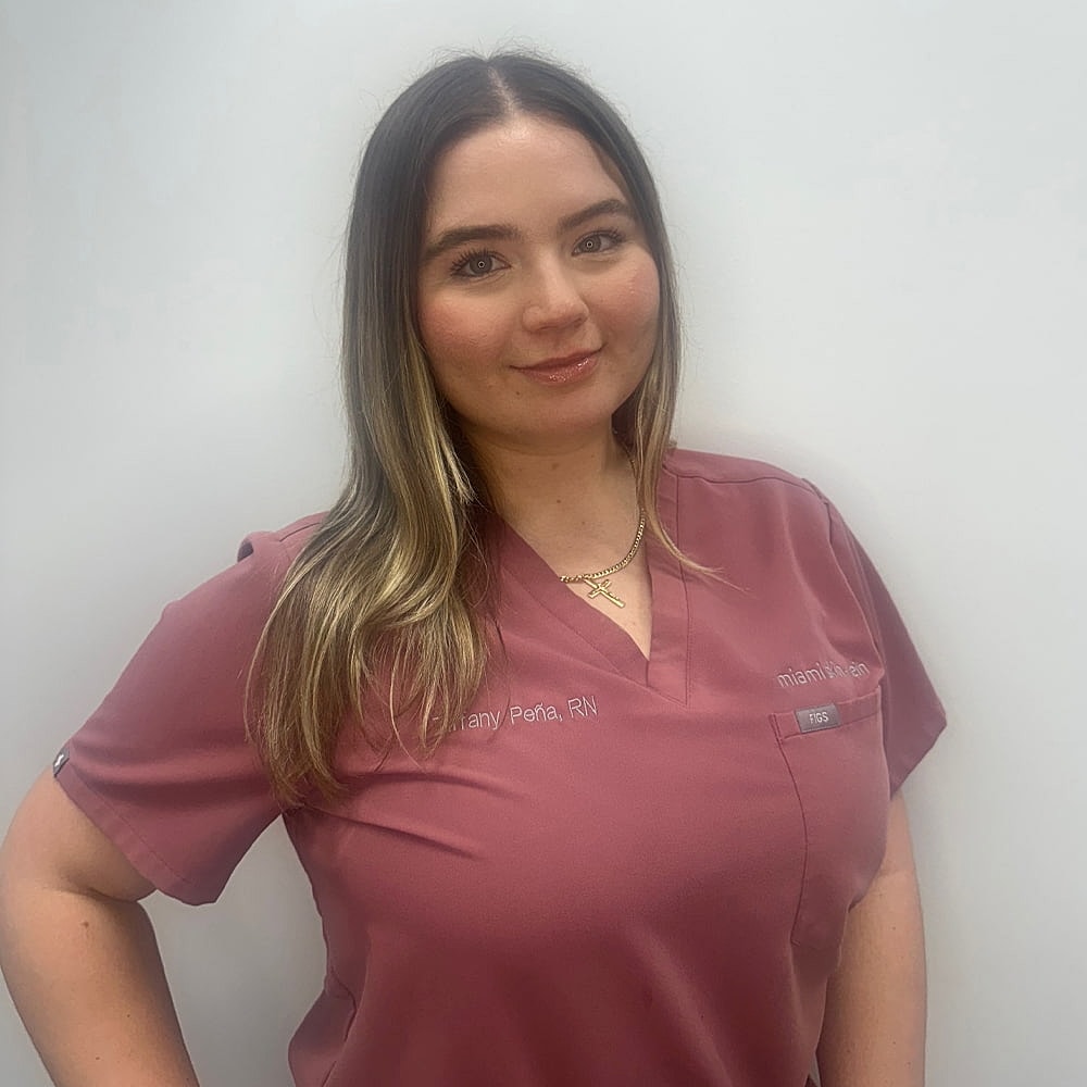 Nurse in scrubs smiling confidently at camera.