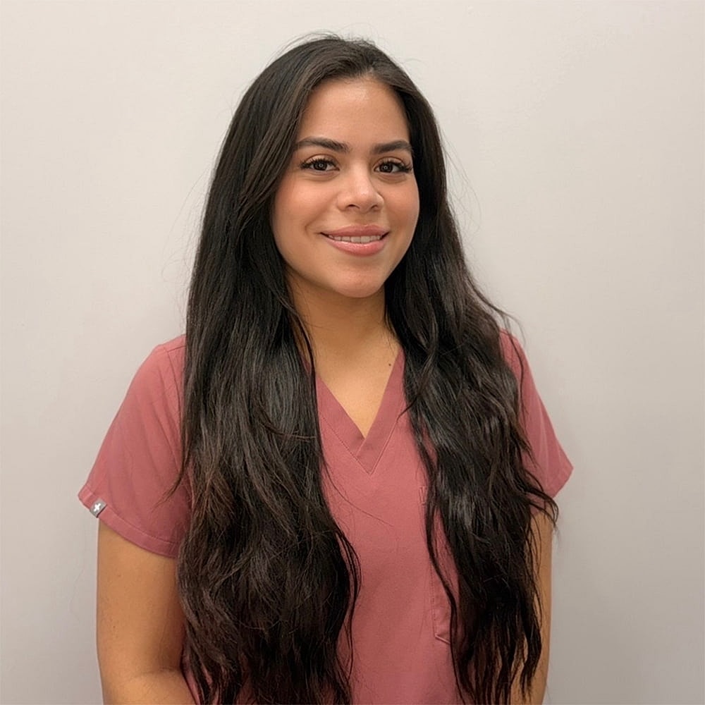 Woman in medical scrubs smiling at camera.