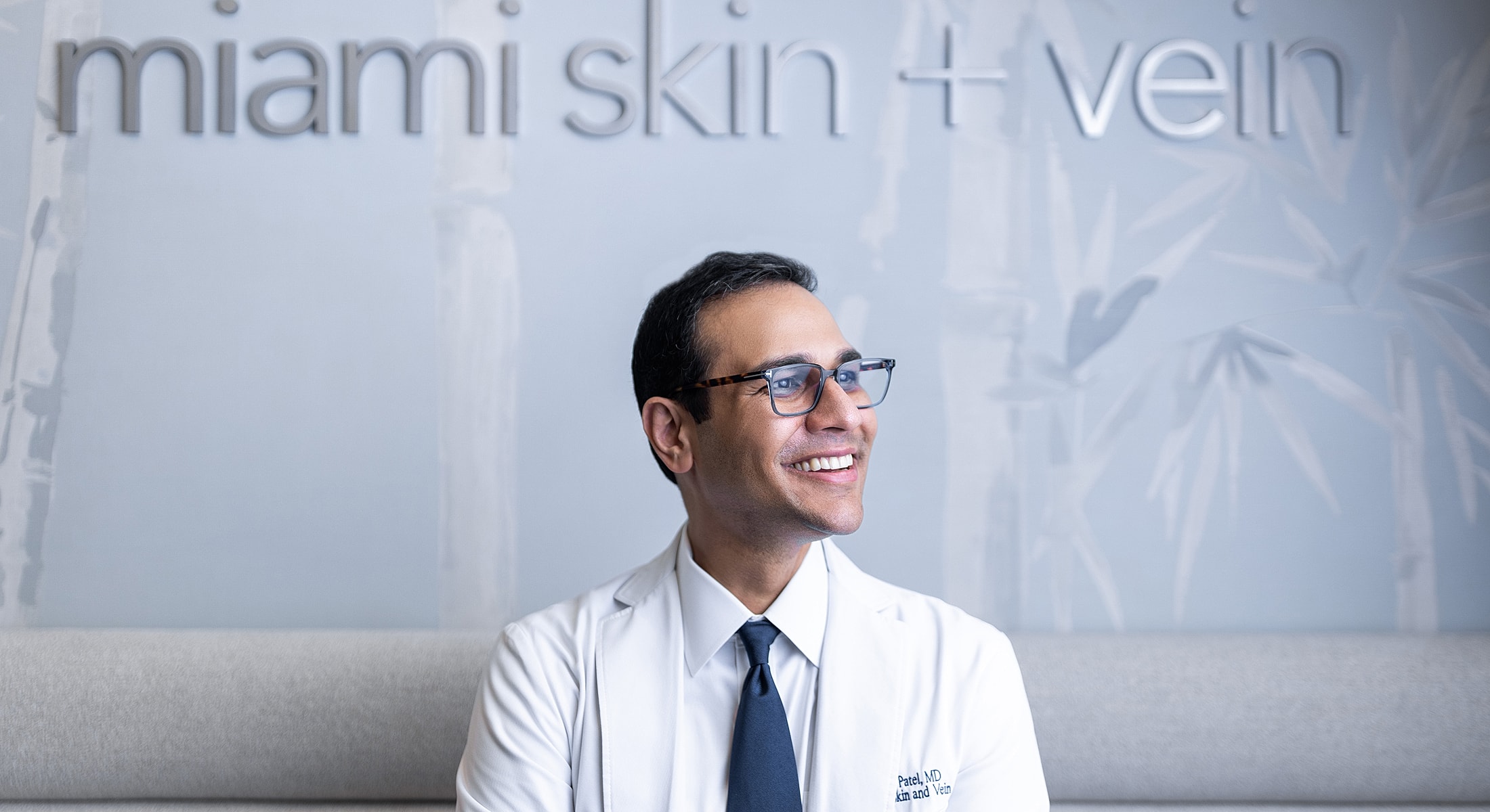 Smiling doctor in front of clinic sign.