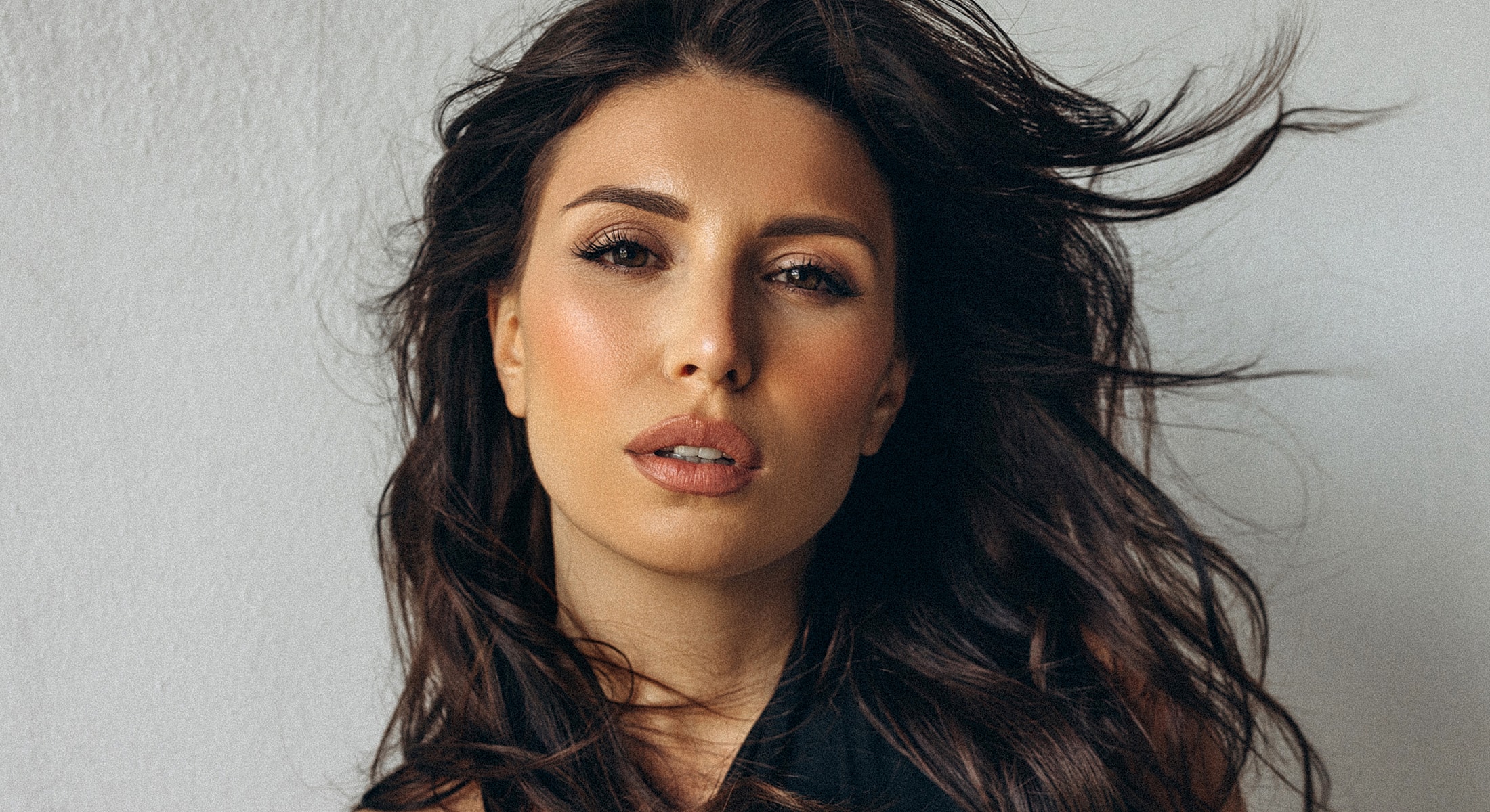 Woman with flowing hair against a neutral background.