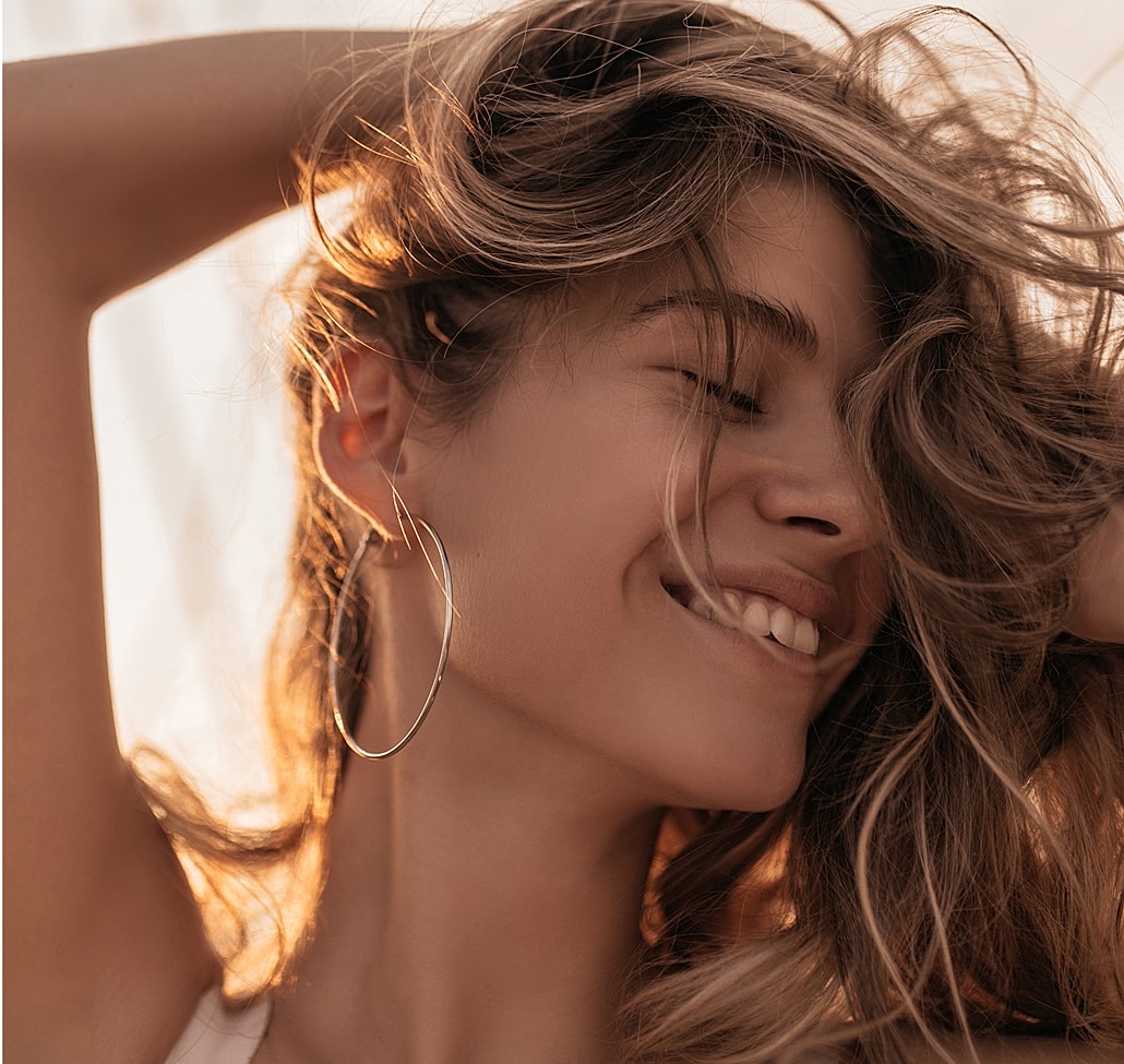 Smiling woman with flowing hair and hoop earrings.