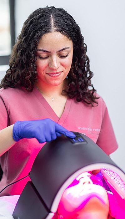 Skin treatment session with LED device and technician.