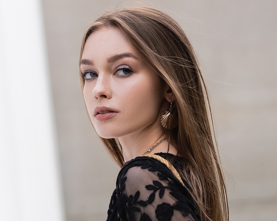 Young woman with long hair and earrings.