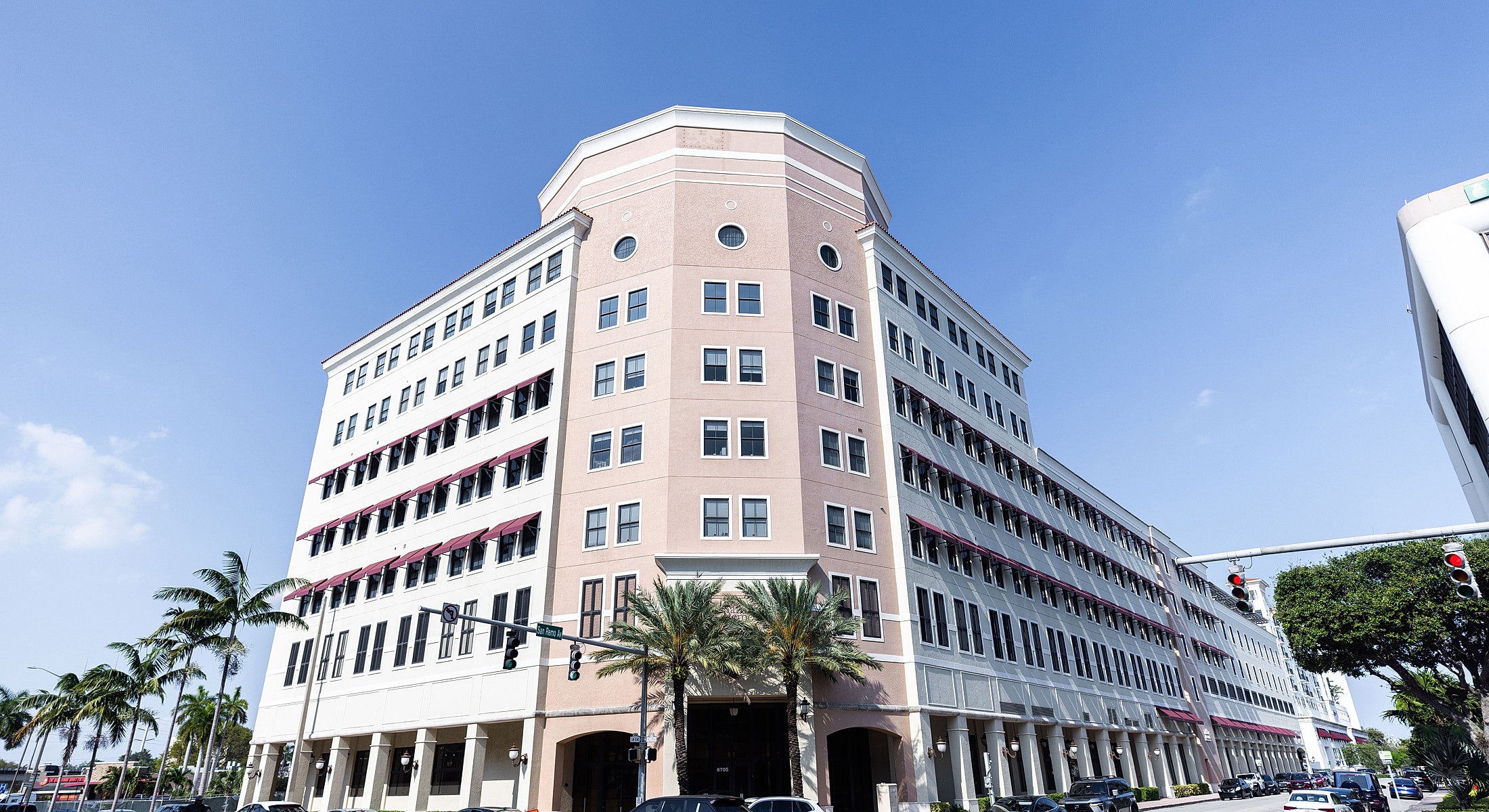 Modern building with palm trees and clear sky.