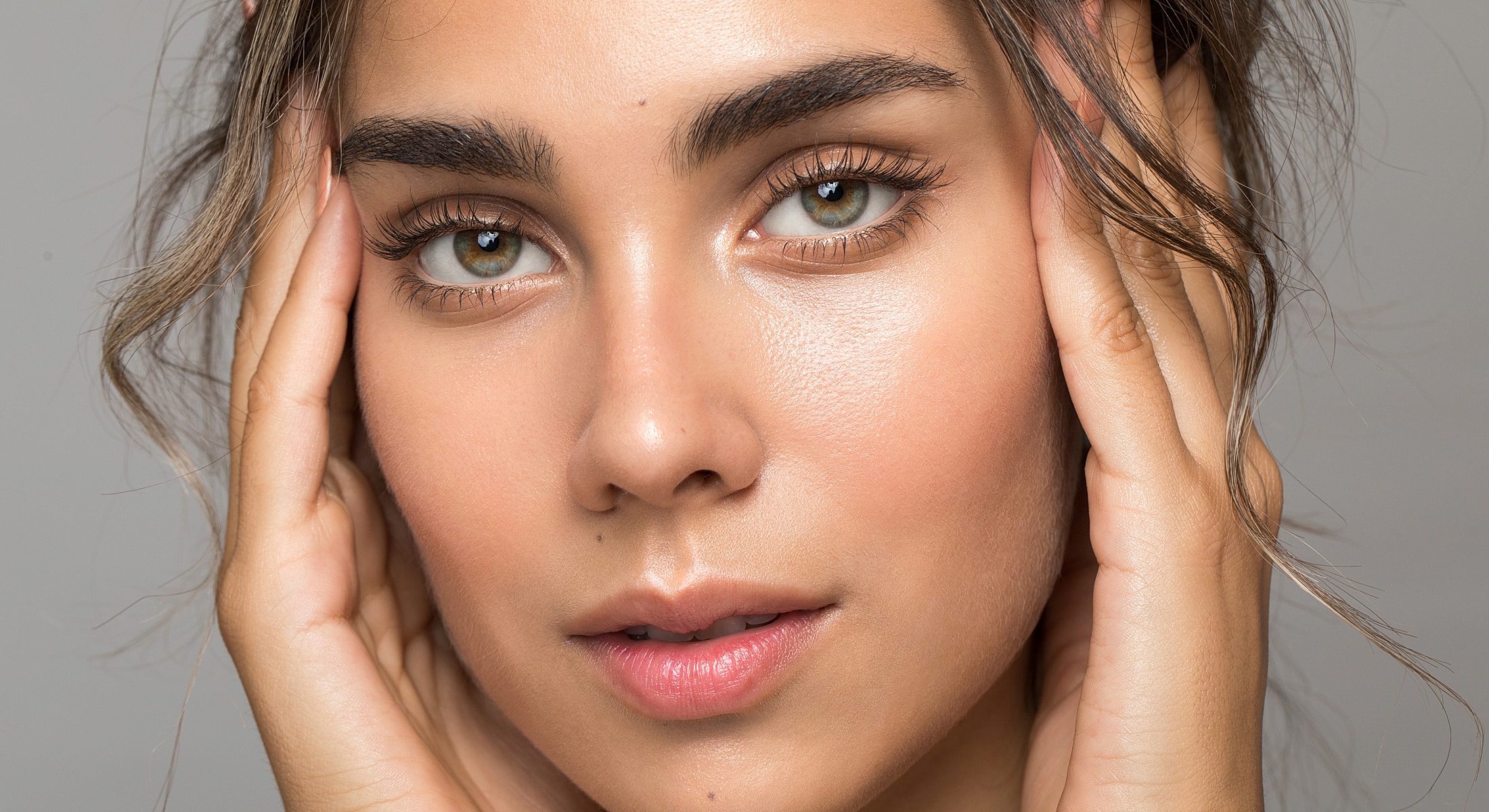 Close-up of a woman touching her face.