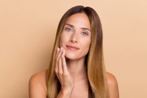 A woman posing with her hand on her chin, showing the results of panfacial rejuvenation at Miami Skin and Vein